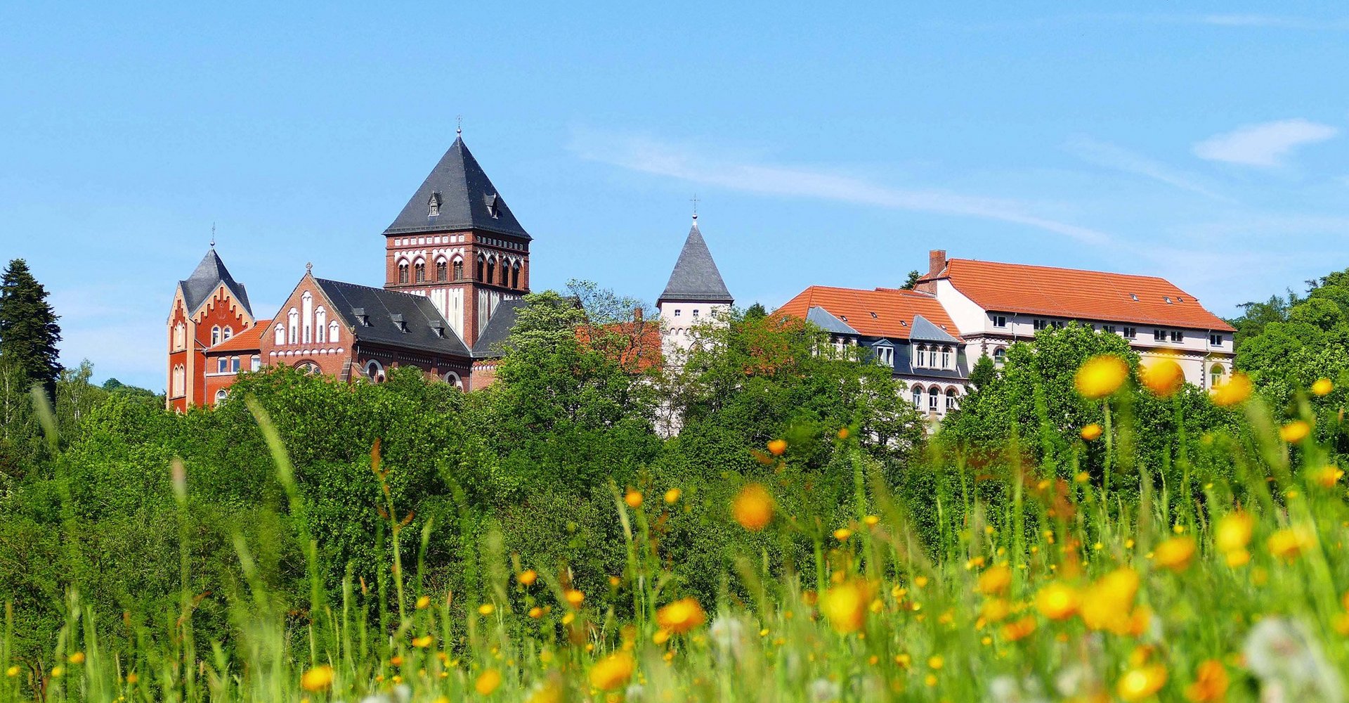 Das Missionshaus mit seiner Missionshauskirche und seinen Gebäuden ist aus rotem Stein gefertigt und liegt auf einem Hügel.