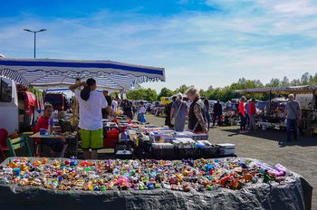 Viele Verkaufsstände stehen auf einer großen Outdoor-Veranstaltungsfläche. Menschen schauen sich die ausgestellten Waren an.