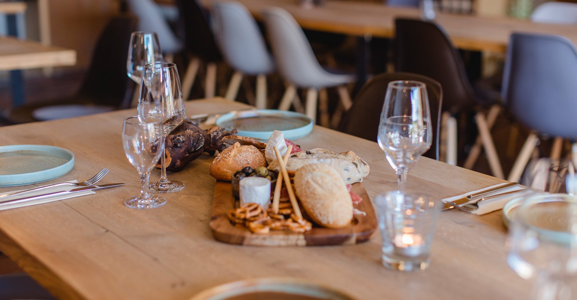 Ein gedeckter Tisch in einem Restaurant. Es stehen Gläser, Teller, Dekoration und Essen auf dem Tisch.