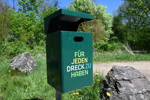 Grüner Mülleimer mit der bunten Aufschrift "Für jeden Dreck zu haben"