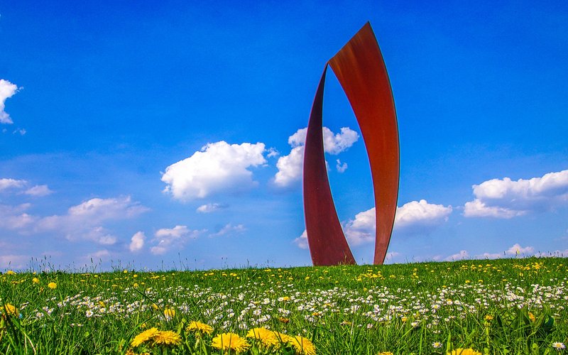 Das Wortsegel ist eine kupferfarbene Stahlplastik, die auf einem Feld steht, und besteht aus zwei jeweils segelförmigen Dreiecken.